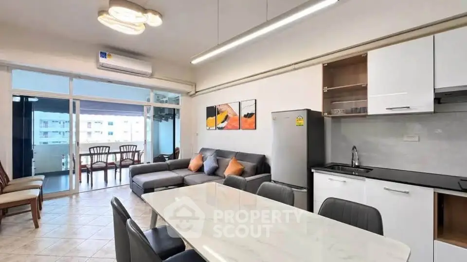 Spacious modern living room with open kitchen and balcony view, perfect for urban living.