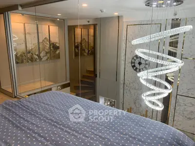 Luxurious bedroom with modern chandelier and glass walls overlooking staircase.