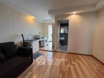 Modern apartment interior with open layout, featuring a cozy living area and compact kitchen with washing machine.
