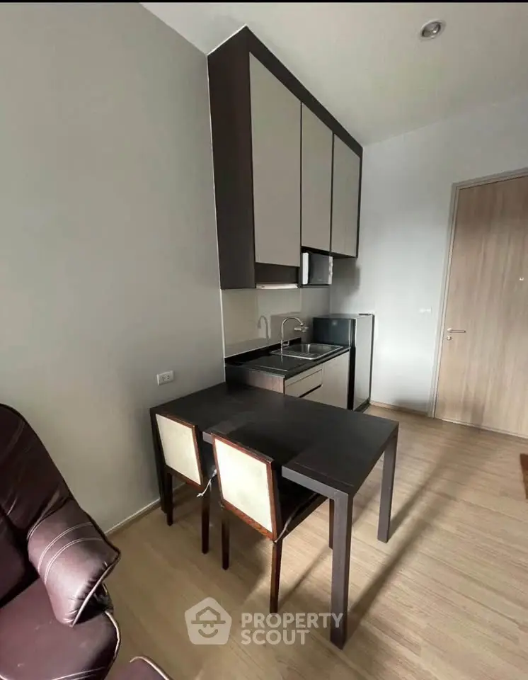 Modern compact kitchen with sleek cabinetry and dining area in cozy apartment