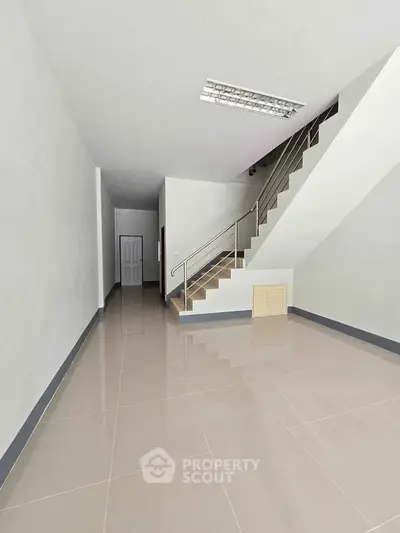 Spacious modern interior with sleek staircase and glossy tiled flooring, perfect for contemporary living.