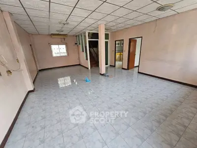 Spacious empty room with tiled floor and unique ceiling design, ideal for customization.