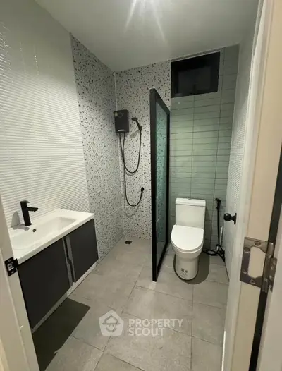 Modern bathroom with sleek design, featuring a shower, toilet, and stylish sink.