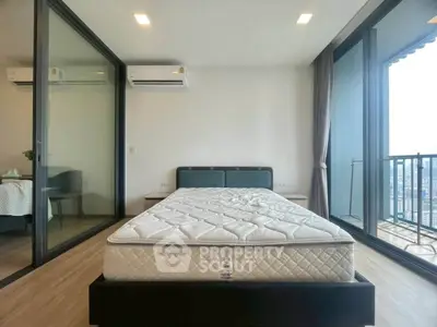 Modern bedroom with large windows and balcony access in a high-rise apartment.