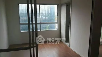 Spacious empty room with large window and wooden flooring