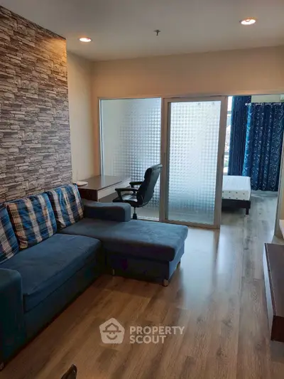 Modern living room with stylish decor and glass partition leading to bedroom