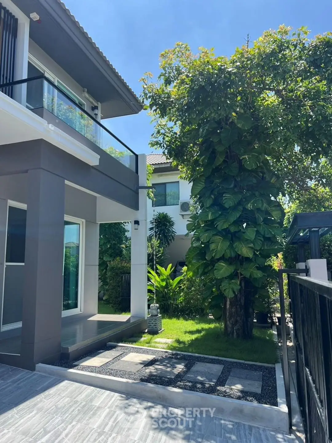 Modern two-story house with lush garden and sleek exterior design.
