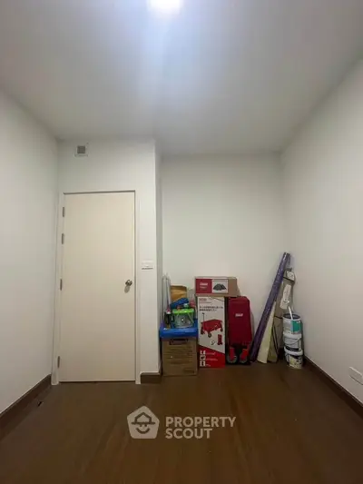 Minimalist storage room with wooden flooring and white walls, ideal for organizing household items.