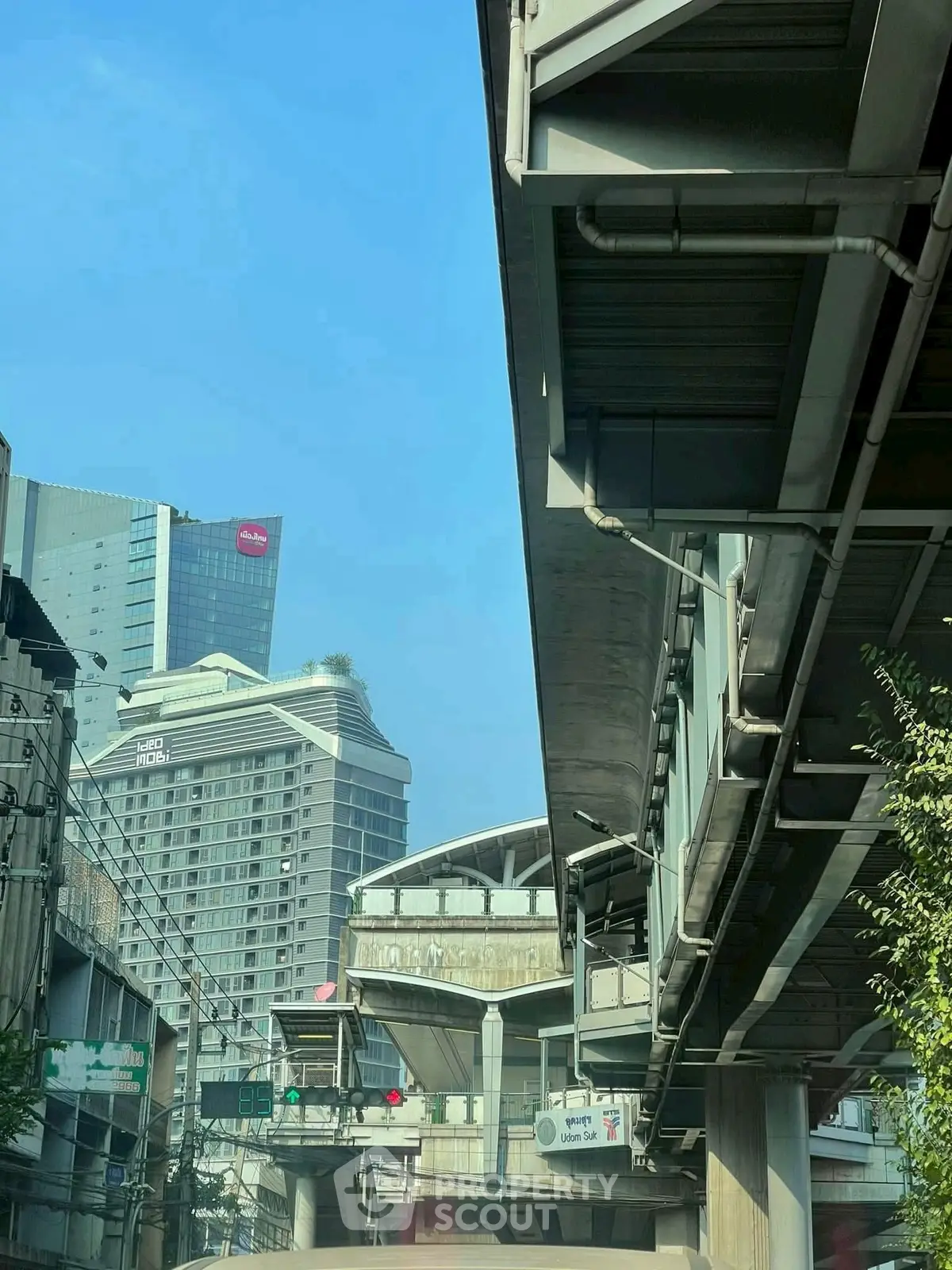 Urban cityscape with modern buildings and elevated train tracks under a clear blue sky.