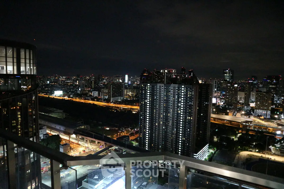 Stunning cityscape view from a high-rise balcony at night, showcasing vibrant city lights and modern architecture.