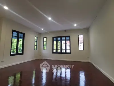 Spacious living room with polished wooden floors and large windows offering natural light.