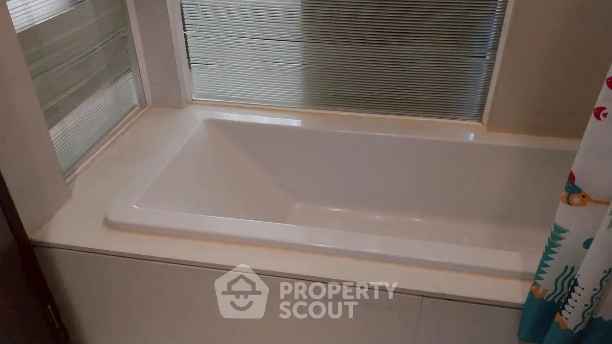 Modern bathroom with sleek bathtub and frosted glass window for privacy.
