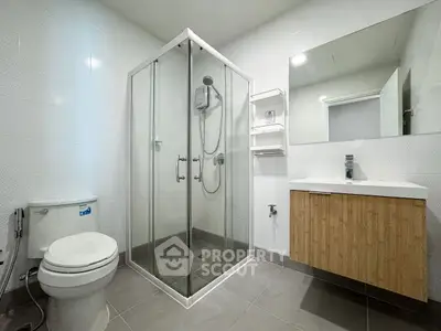 Modern bathroom with glass shower, vanity, and toilet in sleek design.