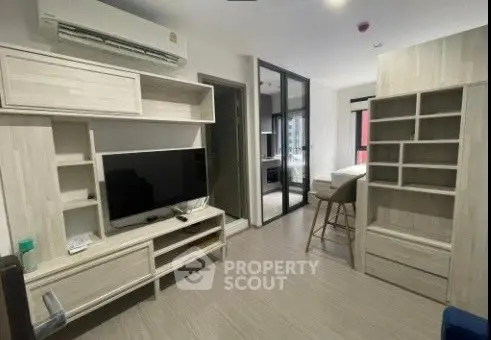 Modern living room with sleek furniture and open layout, featuring a TV and air conditioning.