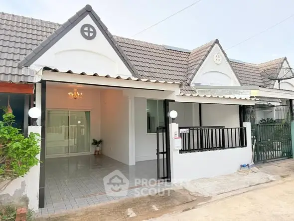 Charming single-story house with tiled roof and gated entrance in a serene neighborhood.