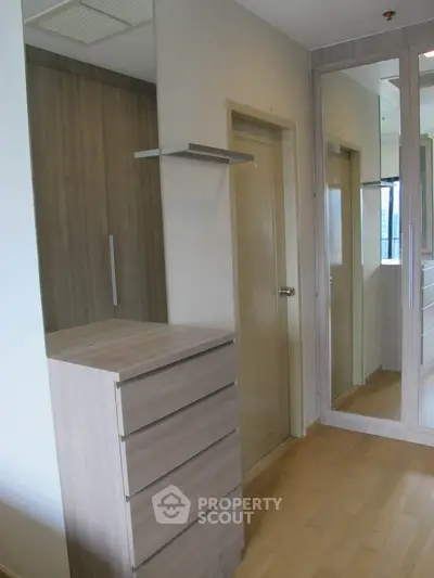 Modern bedroom with mirrored wardrobe and wooden flooring, featuring sleek storage solutions.