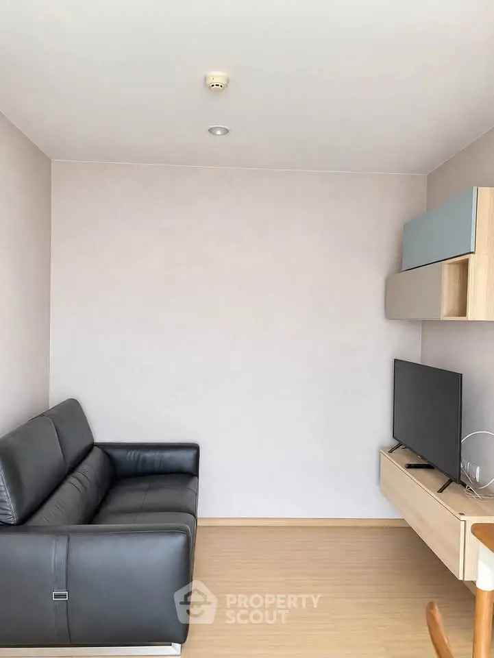 Modern living room with sleek black sofa and mounted TV in minimalist design.