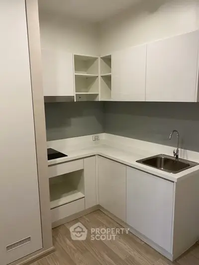 Modern compact kitchen with sleek white cabinets and integrated appliances