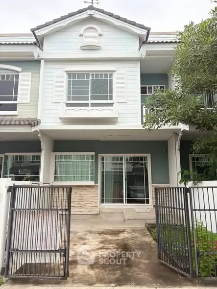 Charming two-story townhouse with gated entrance and lush greenery.