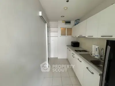 Modern kitchen with sleek white cabinets and tiled flooring in a compact layout.