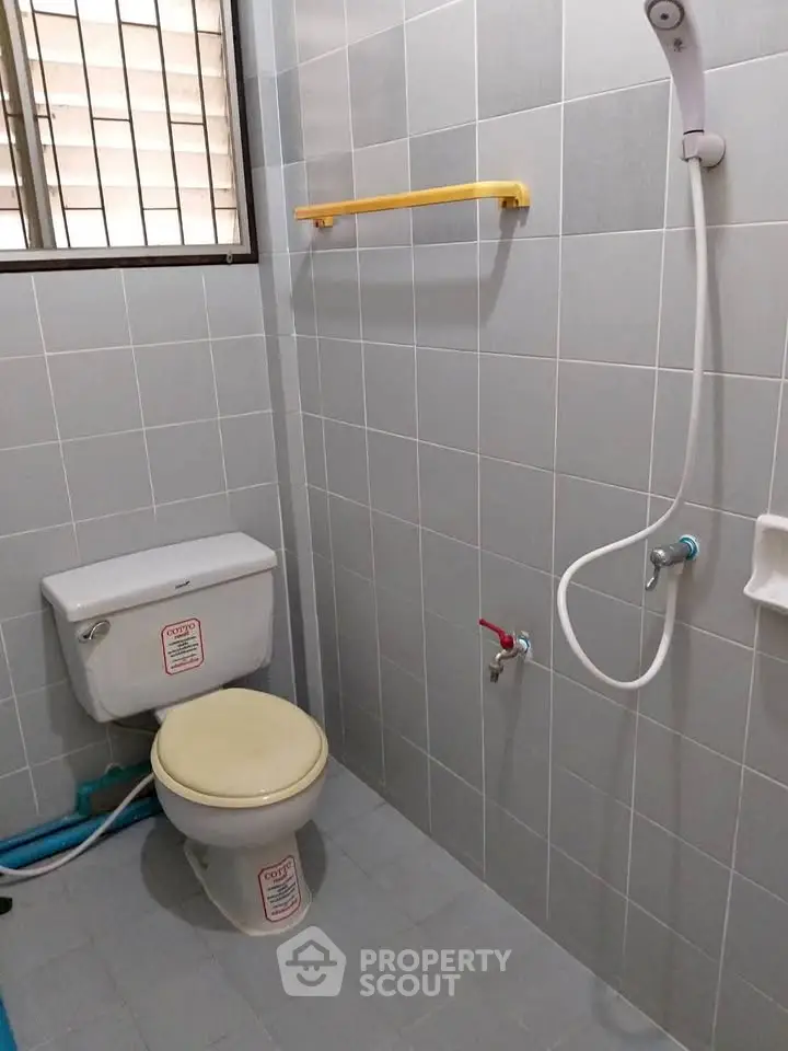 Compact bathroom with shower and toilet, tiled walls and floor, simple and functional design.
