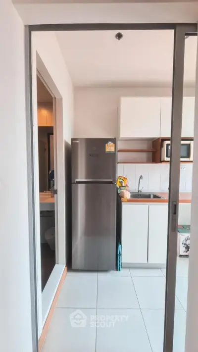 Modern kitchen with stainless steel fridge and sleek cabinetry in a compact layout.