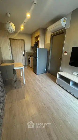 Modern apartment interior with open kitchen and dining area, featuring wooden flooring and contemporary furnishings.