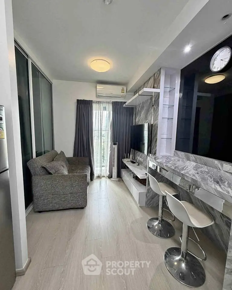 Modern living room with sleek design, featuring a cozy sofa, stylish bar stools, and a wall-mounted TV.