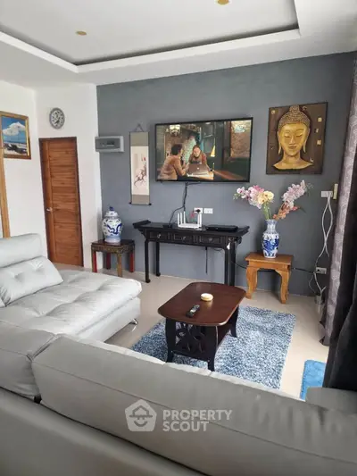 Stylish living room with modern decor, plush white sofas, and elegant Asian art pieces.