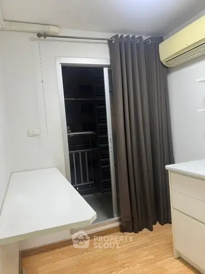 Compact study room with balcony access and air conditioning, ideal for a cozy workspace.