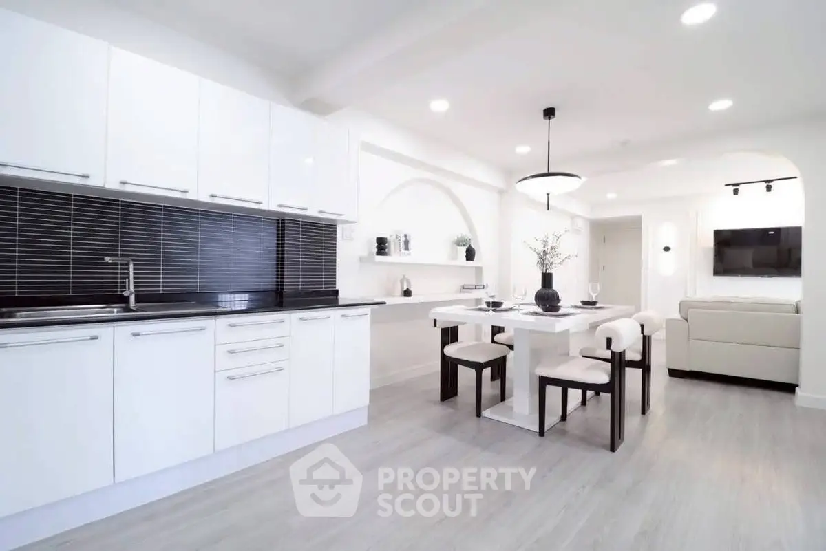 Modern open-layout kitchen and dining area with sleek white cabinets and stylish decor.
