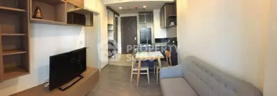 Modern living room with cozy sofa, TV, and dining area in open layout apartment.