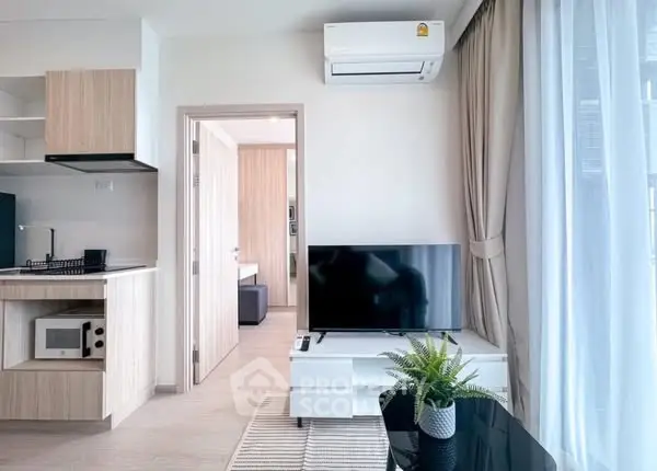 Modern living room with sleek furniture and natural light, featuring a TV and air conditioning unit.