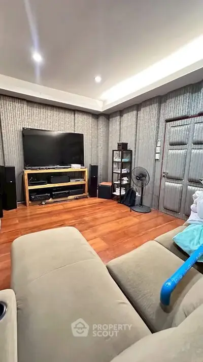 Cozy living room with large TV and comfortable seating, perfect for relaxation.