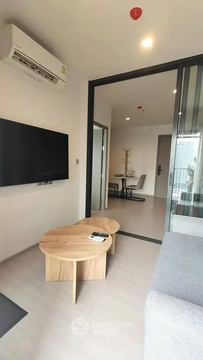 Modern living room with sleek design and open layout, featuring a wall-mounted TV and stylish furniture.