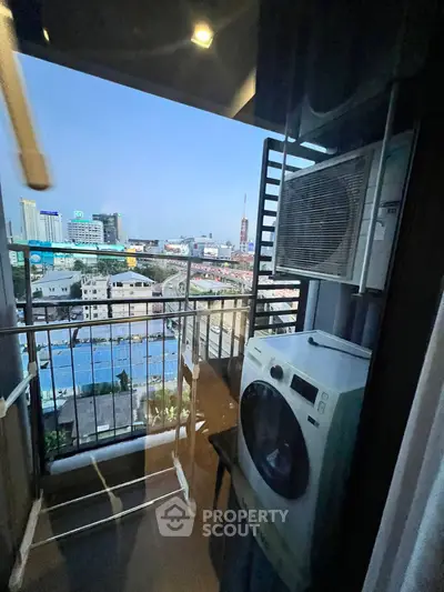 City view from a high-rise balcony with washing machine and air conditioning unit.