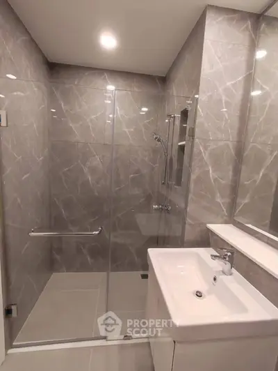 Modern bathroom with sleek marble tiles and glass shower enclosure