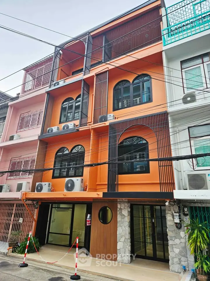 Modern multi-story building with vibrant orange facade and unique architectural design in urban setting.