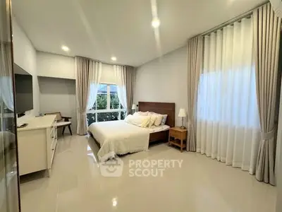 Spacious bedroom with modern decor and large window for natural light