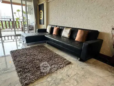 Spacious living room with elegant black sofa and balcony view