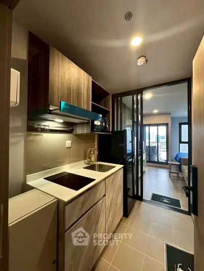 Modern kitchen with sleek cabinetry and open layout leading to living area.