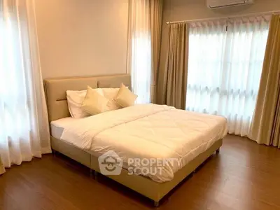 Spacious bedroom with elegant decor and natural light, featuring a comfortable bed and stylish curtains.