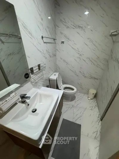 Modern bathroom with sleek white marble tiles and contemporary fixtures.