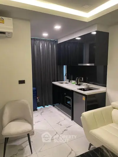 Modern compact kitchen with sleek black cabinets and white countertops in a stylish apartment.