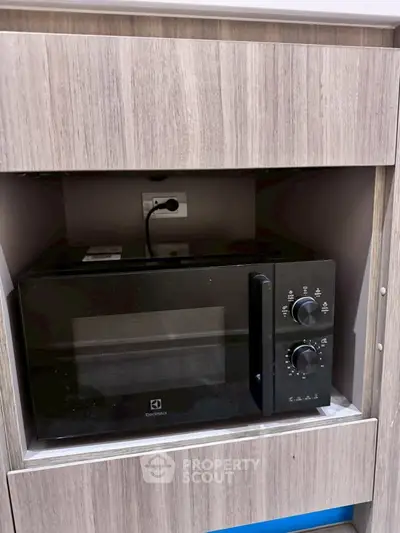 Modern kitchen with built-in microwave oven in sleek wooden cabinetry.