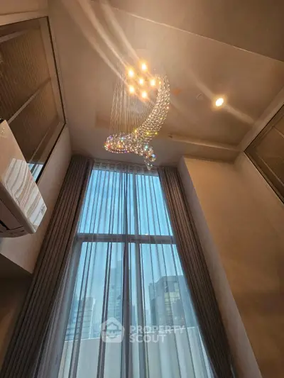 Luxurious high-ceiling room with elegant chandelier and city view.