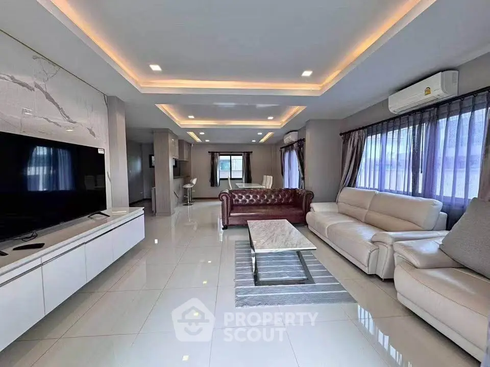 Spacious modern living room with elegant leather sofas and large TV, perfect for relaxation.