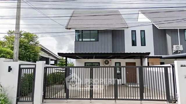 Modern two-story house with sleek design and gated driveway in suburban neighborhood.