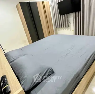 Modern bedroom with sleek design, featuring a comfortable bed, large wardrobe, and wall-mounted TV.
