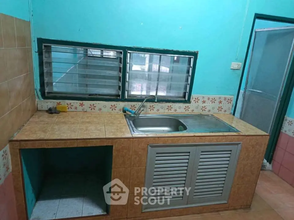 Charming kitchen with tiled countertops and large window, perfect for natural light and ventilation.